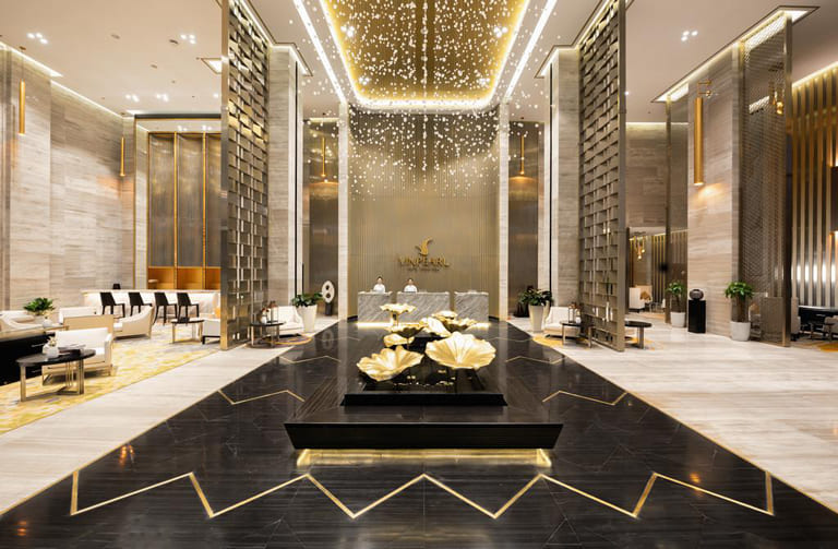 Không gian sảnh đẳng cấp với gam màu vàng - đen chủ đạo, hệ thống trần đèn tinh xảo và cách bố trí nội thất đối xứng, thể hiện đẳng cấp của khách sạn 5 sao.